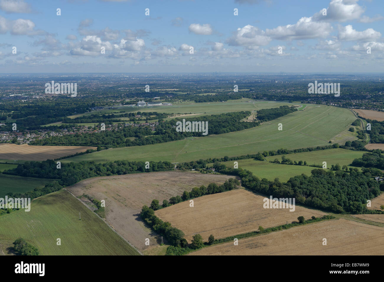 An aerial view of the Epsom Downs with the racecourse visible and the tall buildings of London in the distance Stock Photo
