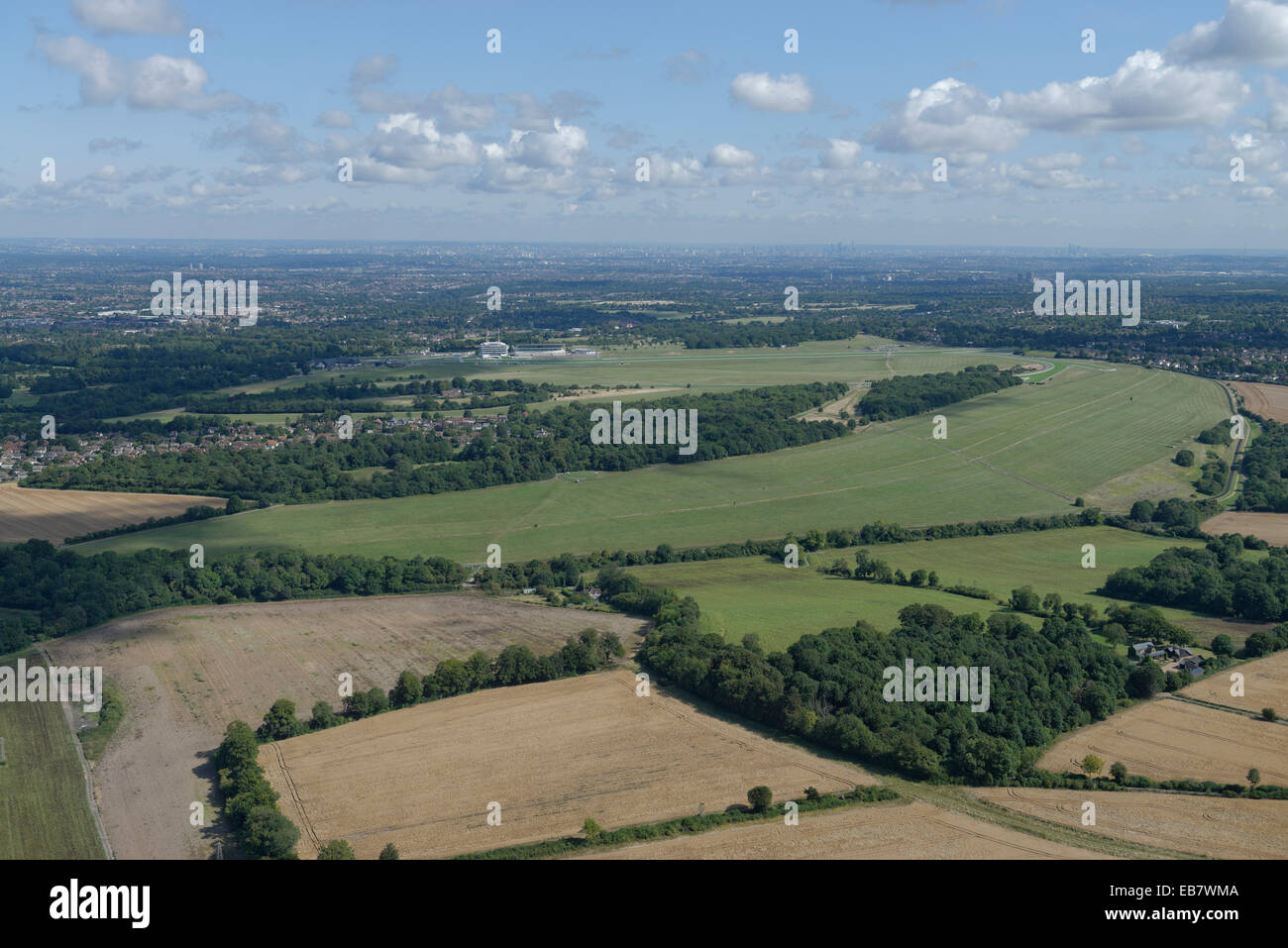 An aerial view of the Epsom Downs with the racecourse visible and the tall buildings of London in the distance Stock Photo