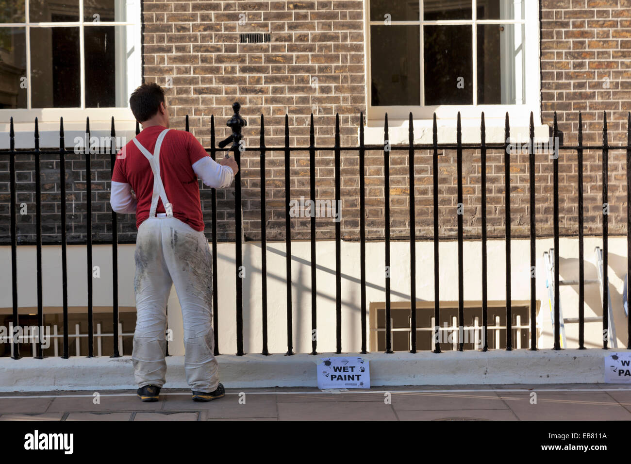 Painter painting railing in Bloomsbury with wet paint signs Stock Photo