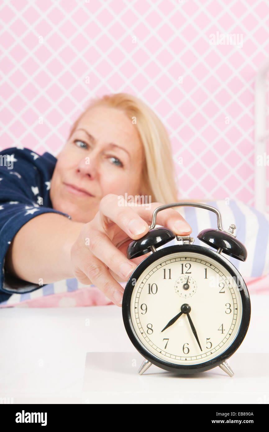 woman of mature age put out the alarm clock in the morning Stock Photo -  Alamy