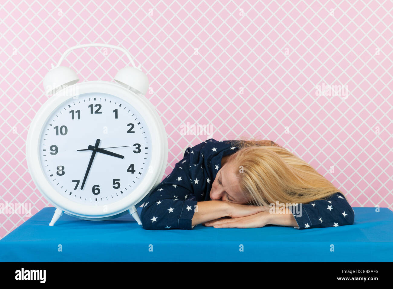 Woman of mature age laying next to big alarm clock Stock Photo