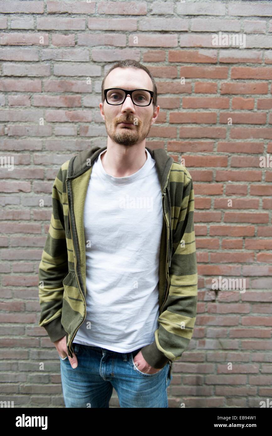 Tilburg, Netherlands. Portrait of a young, slender man with glasses and  facial hair against a brick wall Stock Photo - Alamy