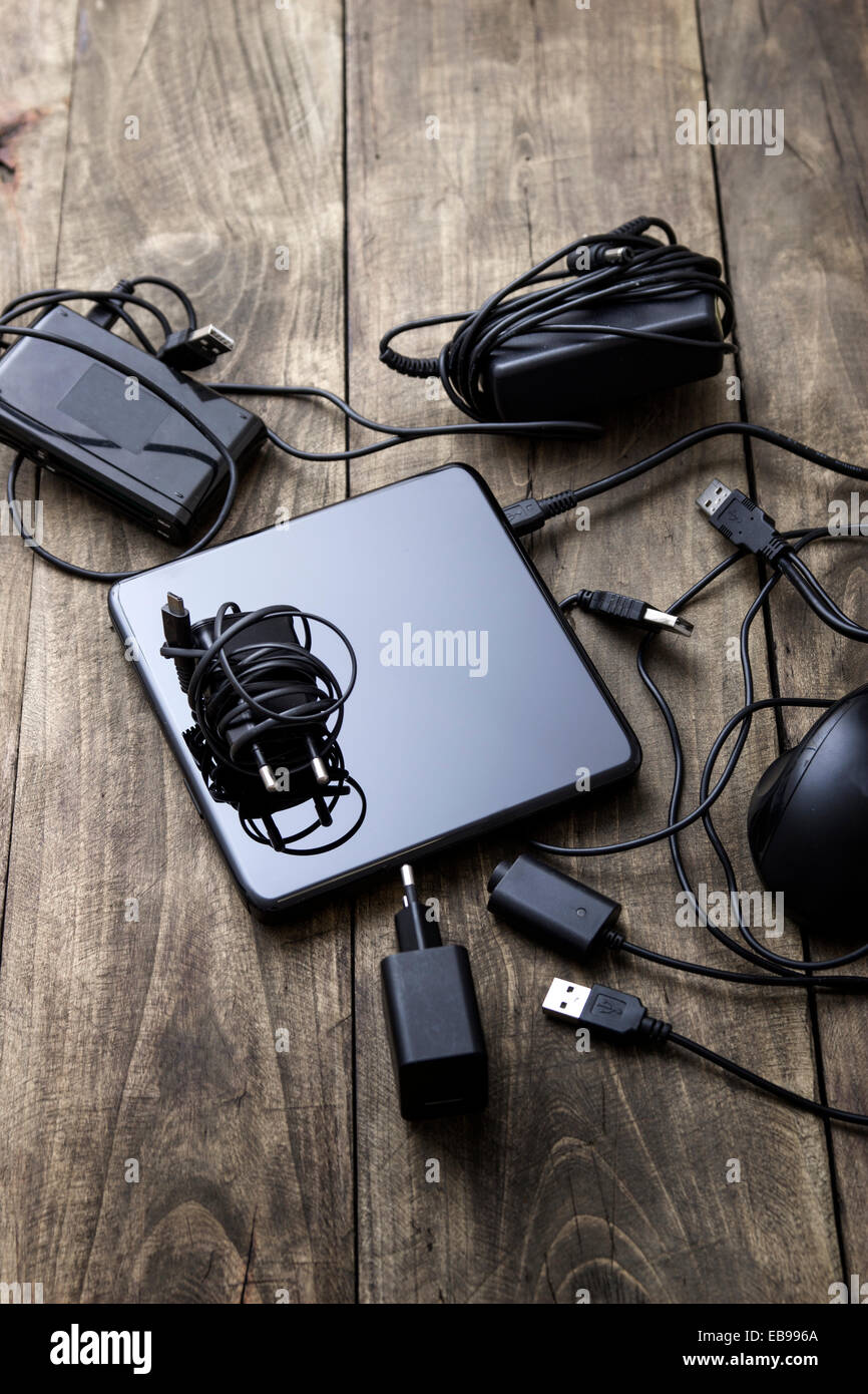 Battery charger and wires tech mess on table Stock Photo