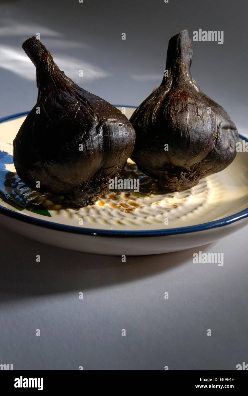 Black garlic bulbs whose unique coffee and chocolate flavor is a result of applying low heat over a period of several weeks Stock Photo