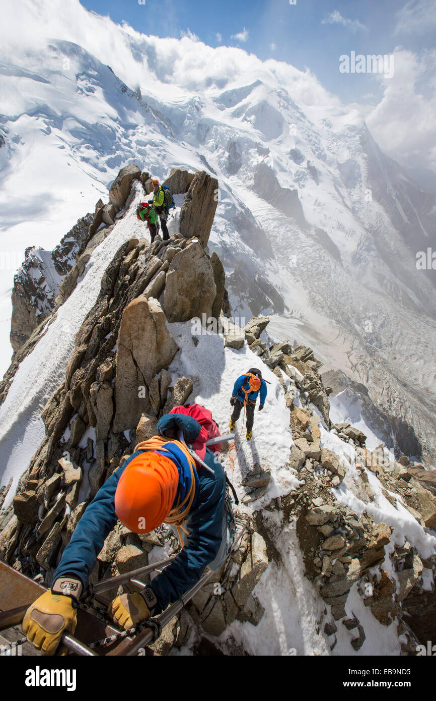 Mont Blanc from the Aiguille Du Midi above Chamonix, France, with climbers on the Cosmiques Arete, climbing the ladder to access the cable car station. Stock Photo