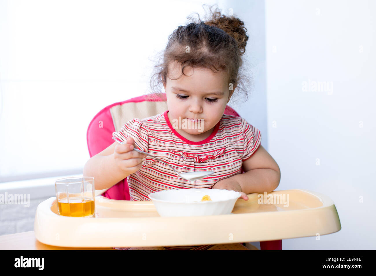 Pretty kid eating with spoon Stock Photo - Alamy