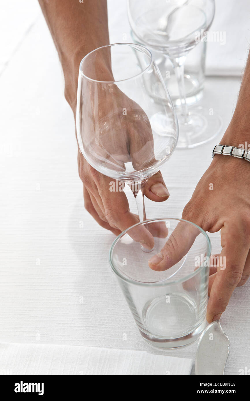 Close up of Waiter's Hands Arranging Glasses on Restaurant Table Stock Photo