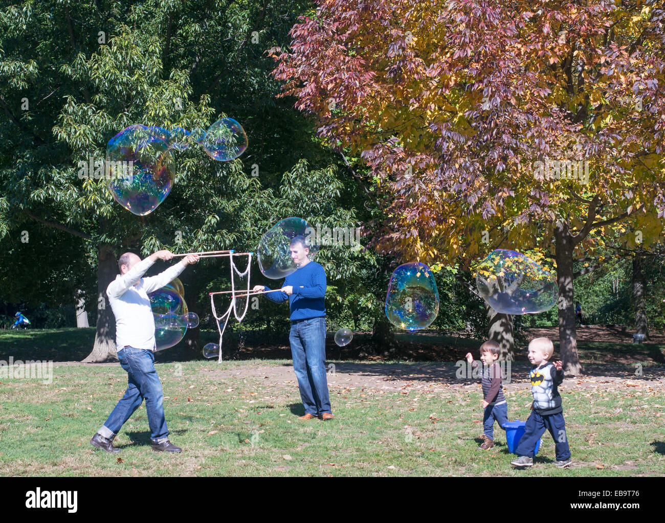 Men making monster soap bubbles with young children watching in Prospect Park Brooklyn, NYC, USA Stock Photo