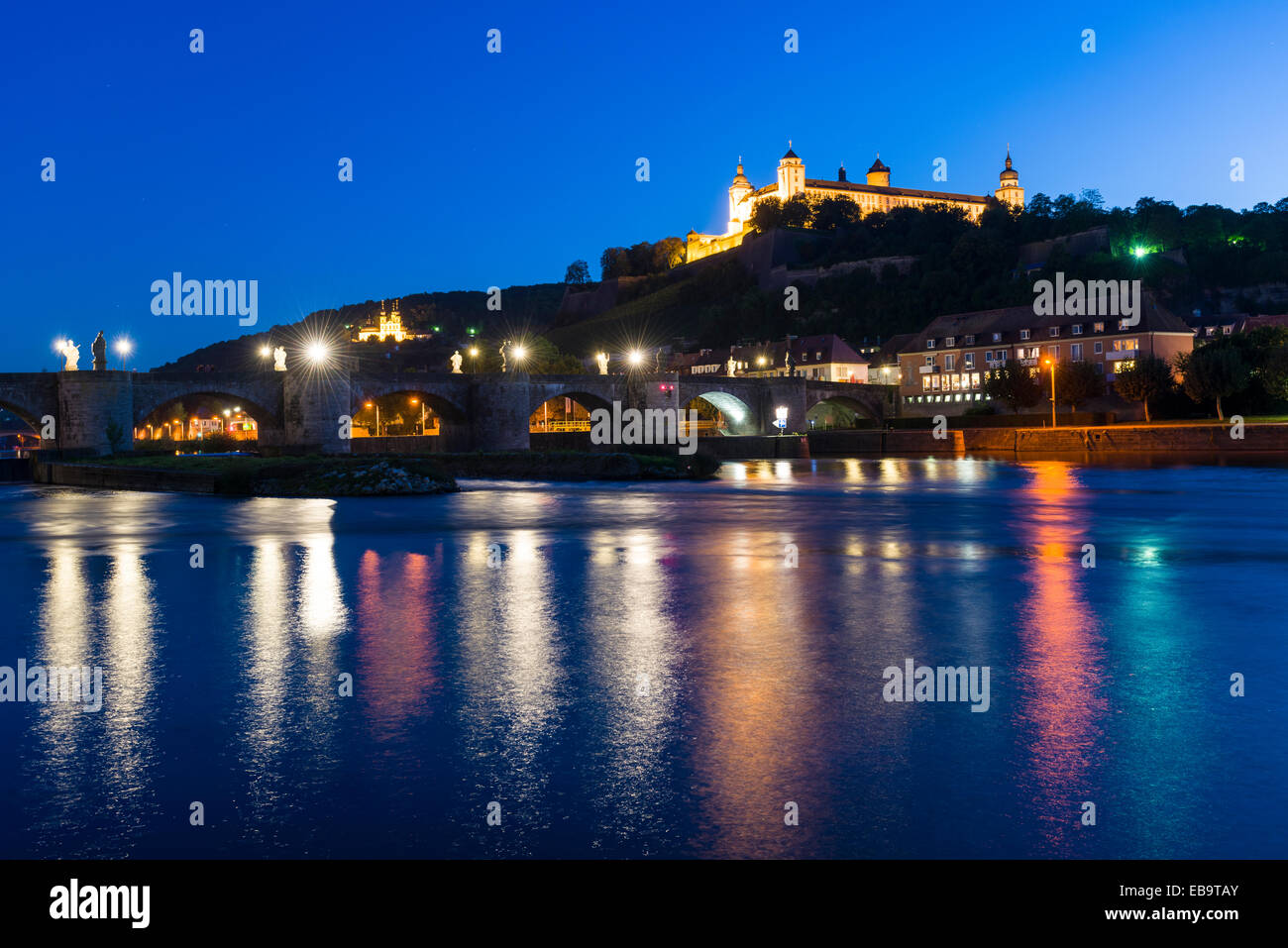 The illuminated Festung Marienberg castle located on a hill above the town, the Alte Mainbrücke bridge crossing the river Main Stock Photo