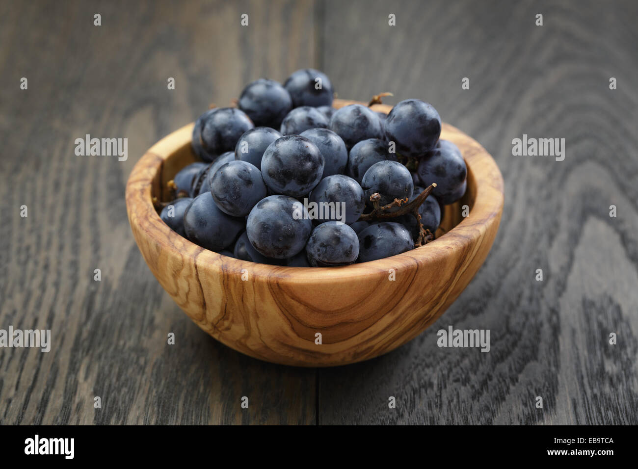 ripe isabella grapes in wood bowl on table, simple rustic photo Stock Photo