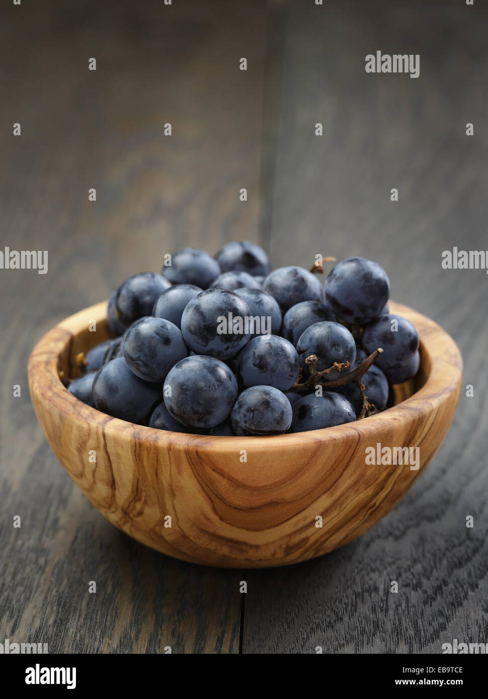 ripe isabella grapes in wood bowl on table, simple rustic photo Stock Photo