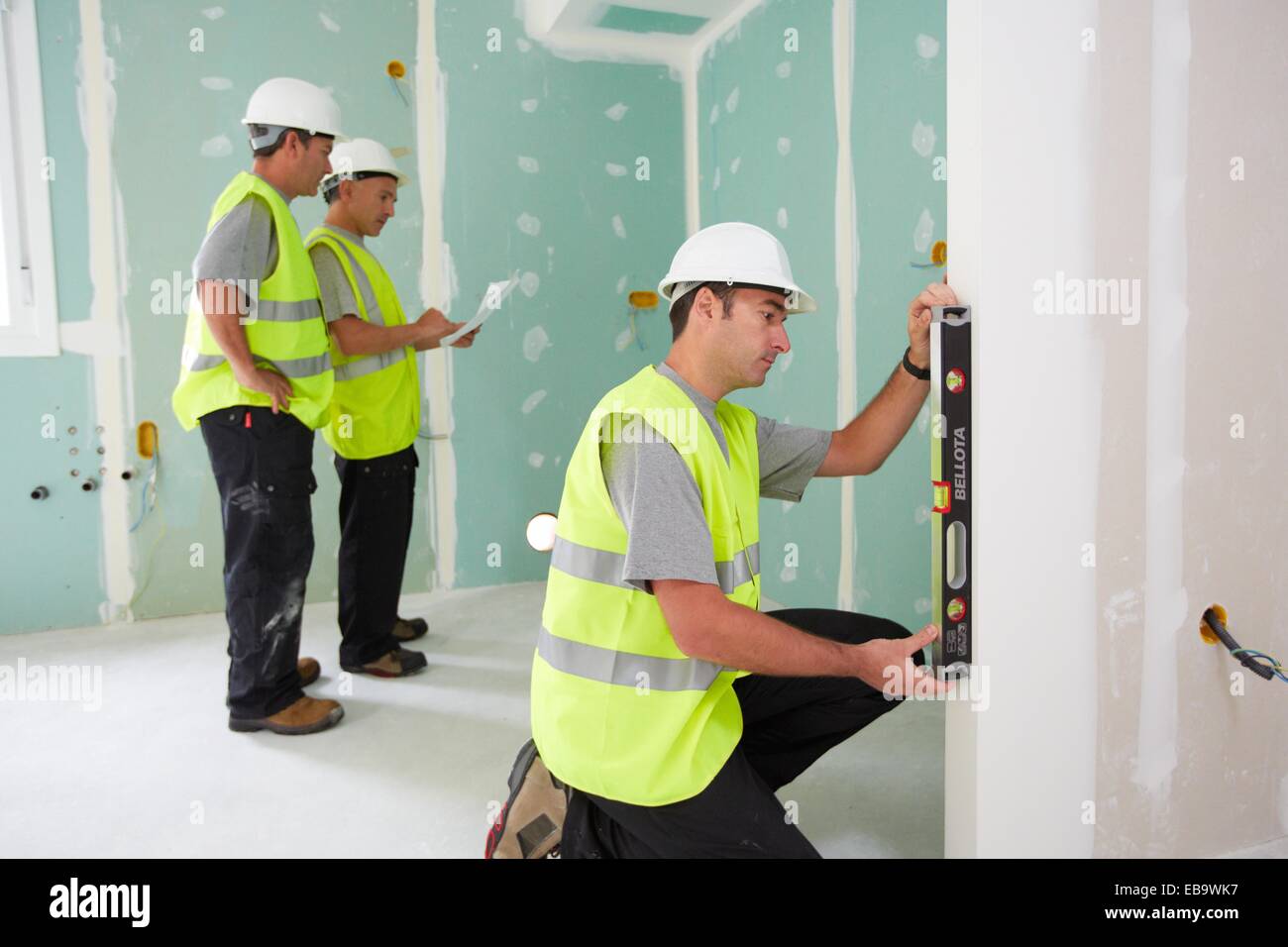 Worker with protective equipment PPE Leveling plasterboard panels