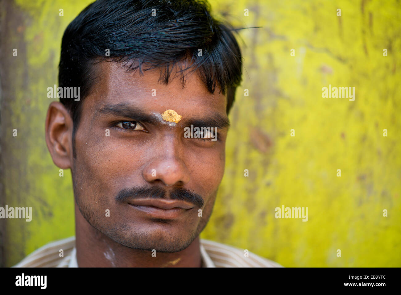 Man in front of lemon-yellow wall with bindi on his forehead, portrait, Meenakshi Amman Temple or Sri Meenakshi Sundareswarar Stock Photo