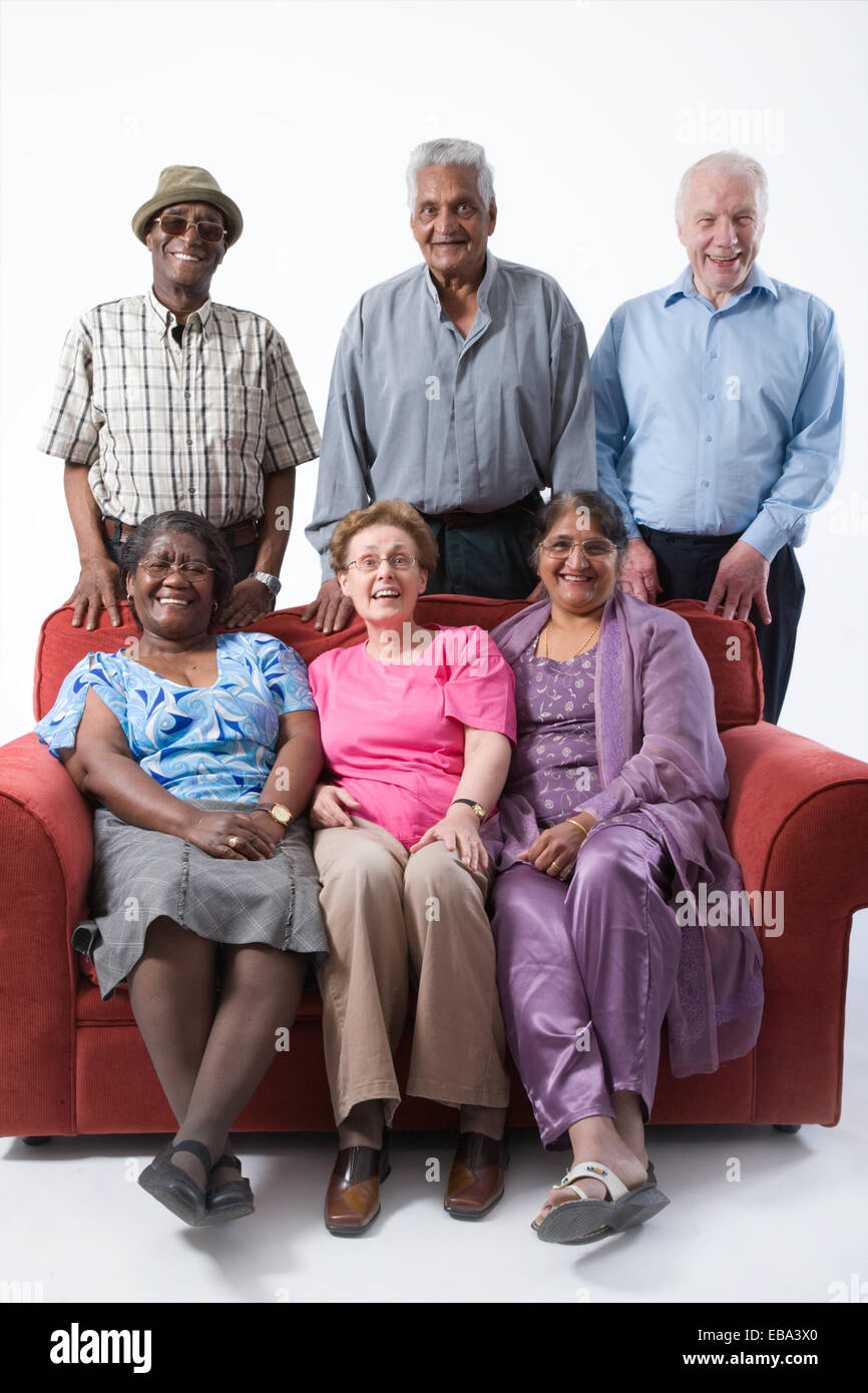 Multiracial group of older people sitting on a sofa together smiling, Stock Photo