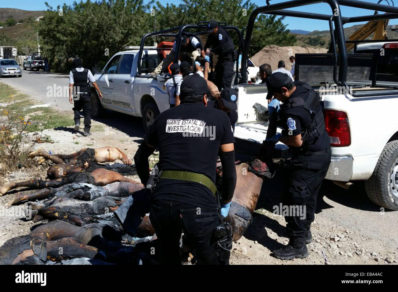 Guerrero, Mexico. 27th Nov, 2014. Security members carry the bodies of victims found in an offroad trail, close to Chilapa's municipality, Guerrero state, Mexico, on Nov. 27, 2014. Eleven persons were shot, decapitated and burnt after being involved in a fight between alleged members of drug cartels, according to the local press. © Edgar de Jesus Espinoza/Xinhua/Alamy Live News Stock Photo