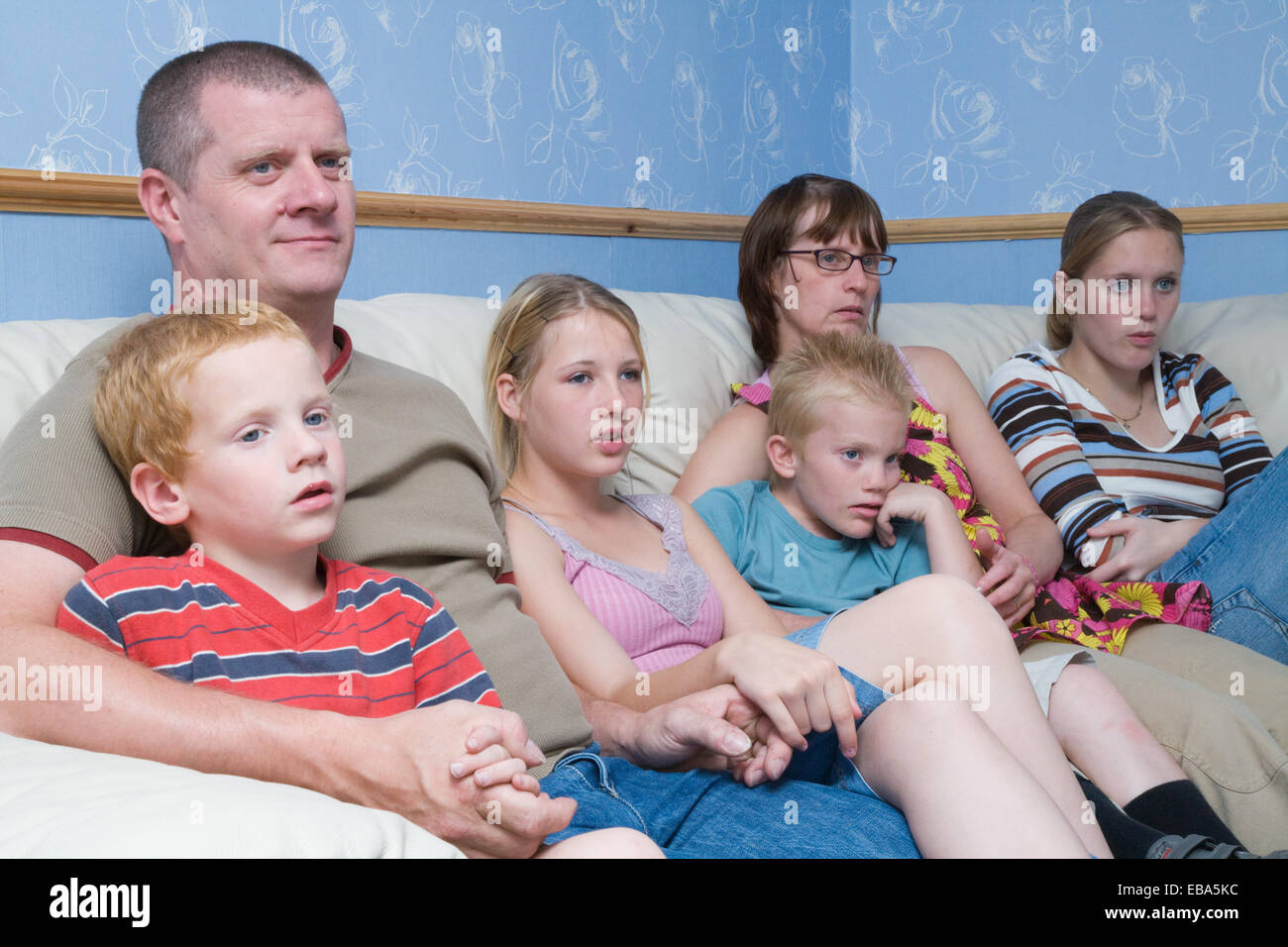 Family sitting on the sofa watching television together, Stock Photo