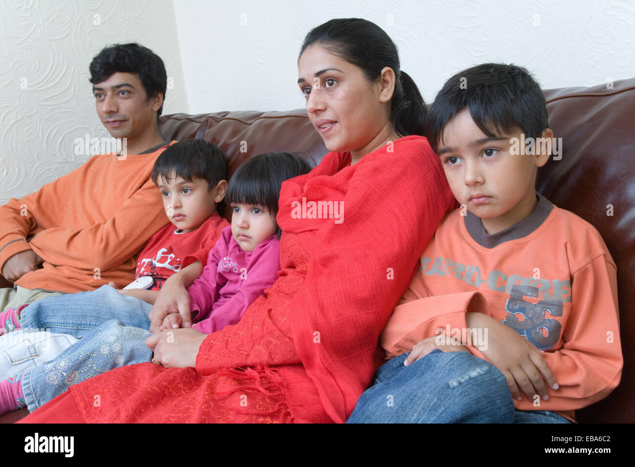 Young family sitting on the sofa watching television together, Stock Photo