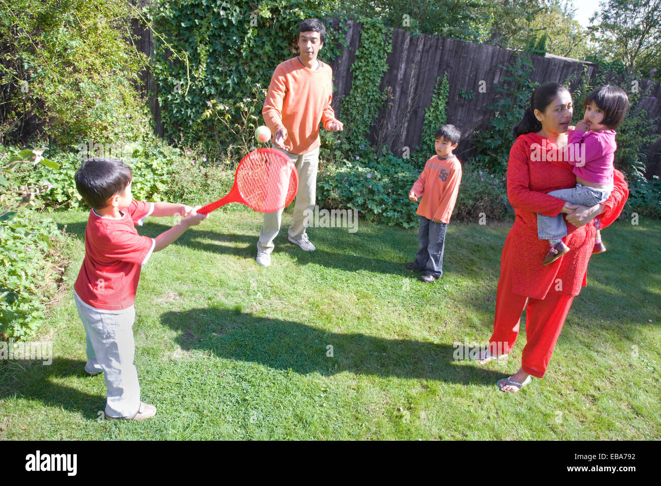 Young family playing with a racket and ball in the garden Stock Photo ...