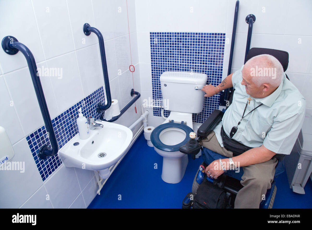 Male wheelchair user flushing the loo in wheelchair accessible WC, Stock Photo