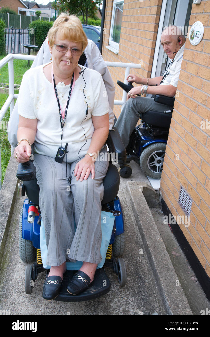 Disabled couple leaving their house down a concrete wheelchair ramp