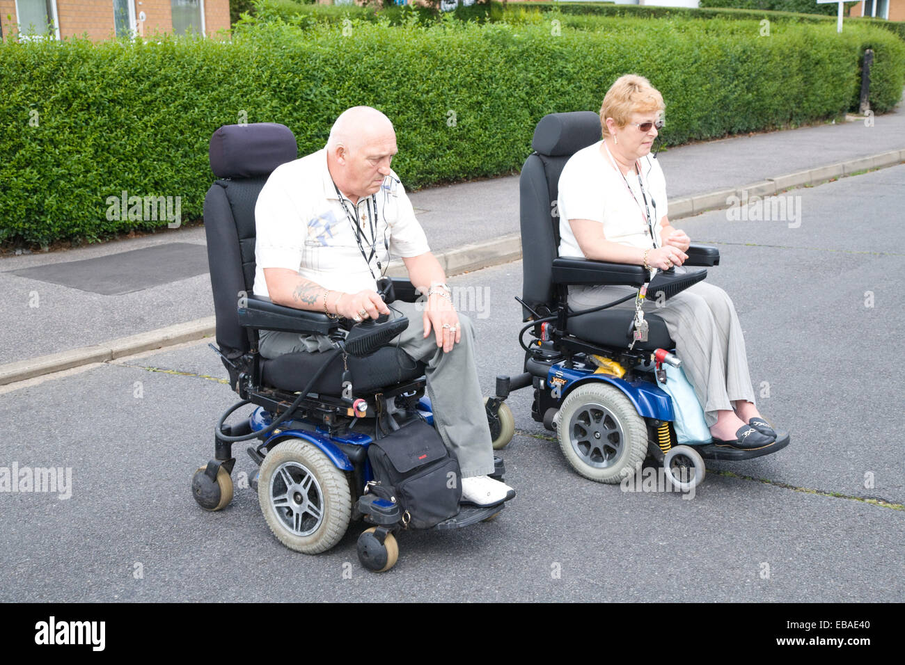 Disabled couple crossing the road in motorised wheelchairs Stock Photo