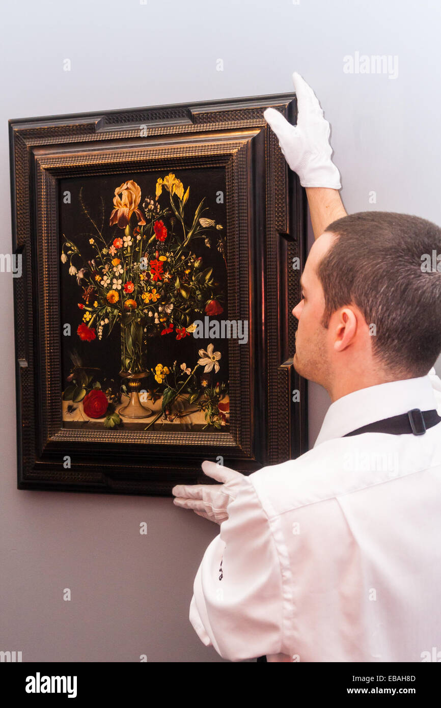 Sotheby's London, UK. 28th Nov, 2014. Sotheby's hold a preview for their December 3rd sale of Old Master and British Paintings at their Bond Street gallery. The exhibition runs from November 29th to December 3rd. PICTURED: A Sotheby's gallery tedchnician hangs Ambrosius Bosschaert the Elder's 'Still life of flowers including irises, lillies, narcissi, lilly-of-the-valley and carnations in a tall glass vase, set on a stone ledge', which was painted in 1606. It has an estimated value of up to £900,000 at auction. Credit:  Paul Davey/Alamy Live News Stock Photo