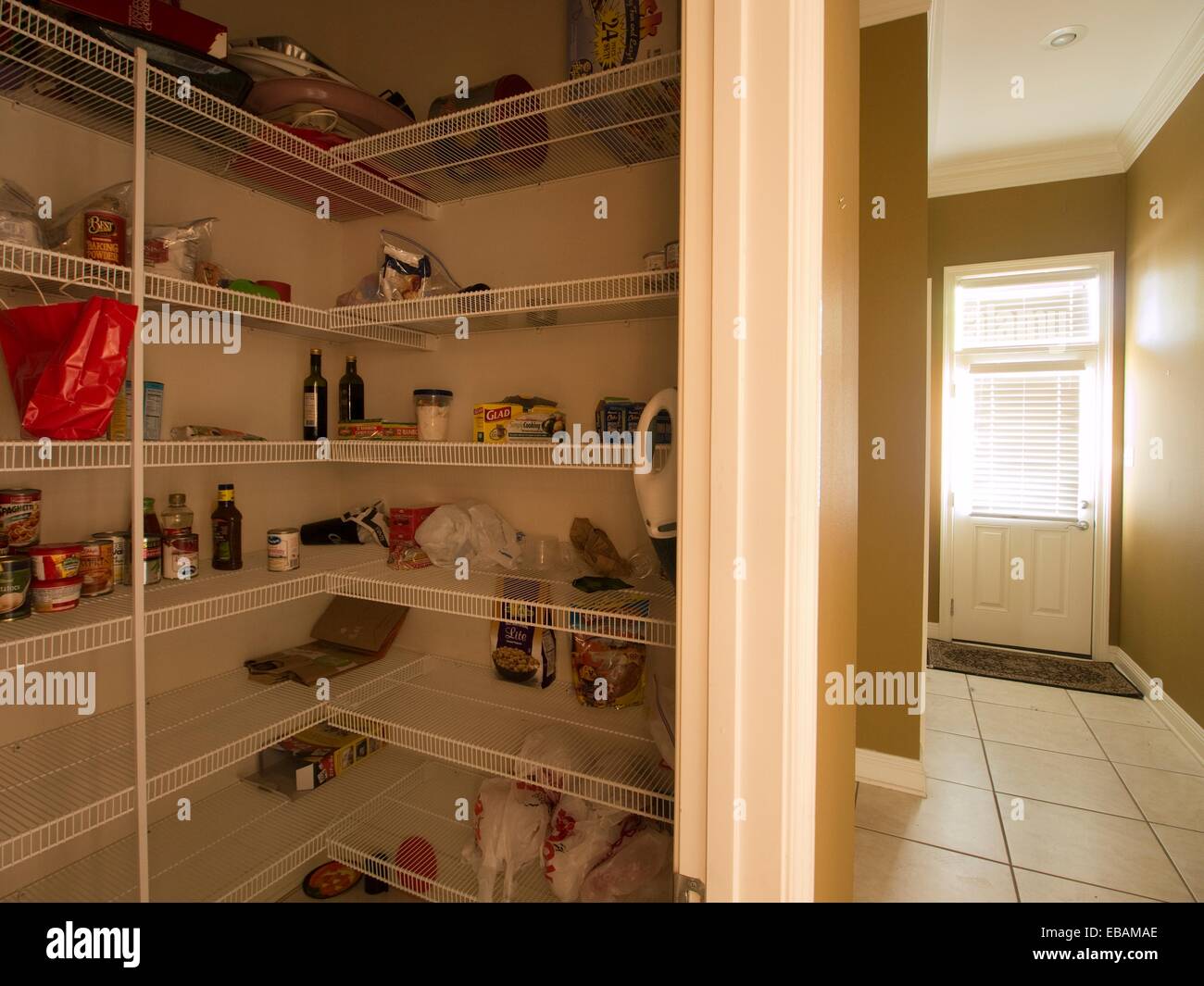 The shelves of an empty pantry contain only a few food items inside a