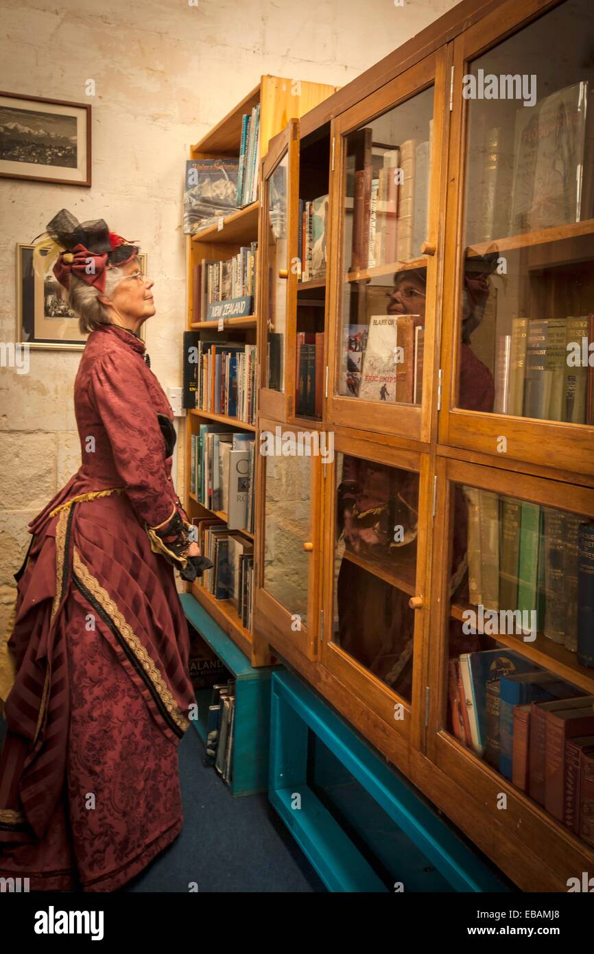 Lady in Victorian costume views antique books during Victorian festival historic precinct Oamaru Otago Stock Photo
