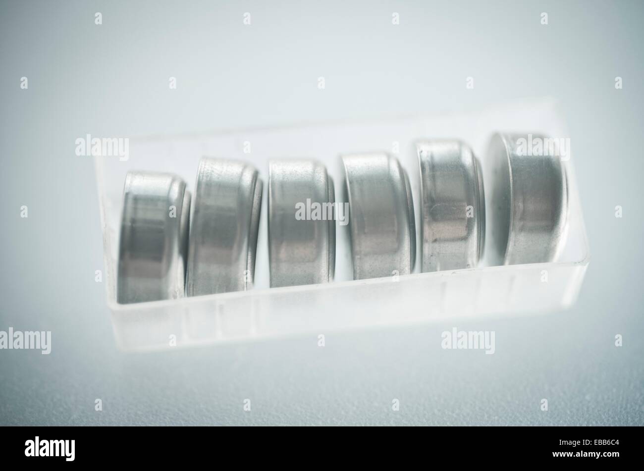 Button cells in row within a transparent plastic container. Batteries