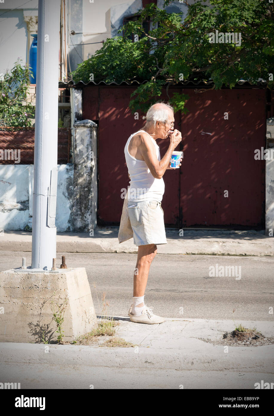 HAVANA , CUBA -  MAY 5, 2014: Elder unidentified eating yoghurt on the streets of Vedado district in Havana, Cuba Stock Photo