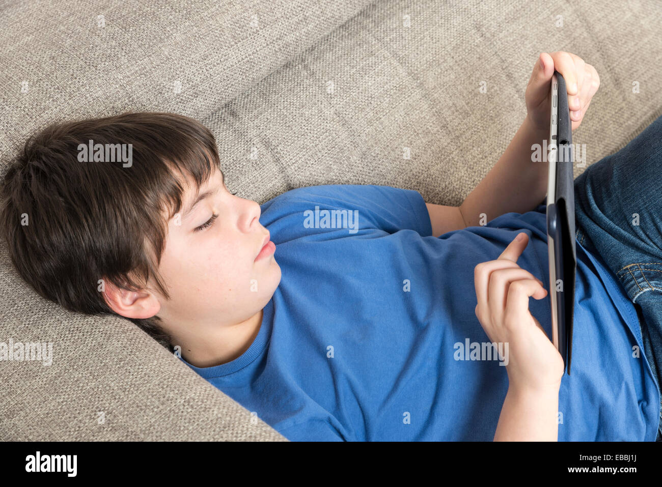 Young boy using tablet digital on the sofa Stock Photo - Alamy