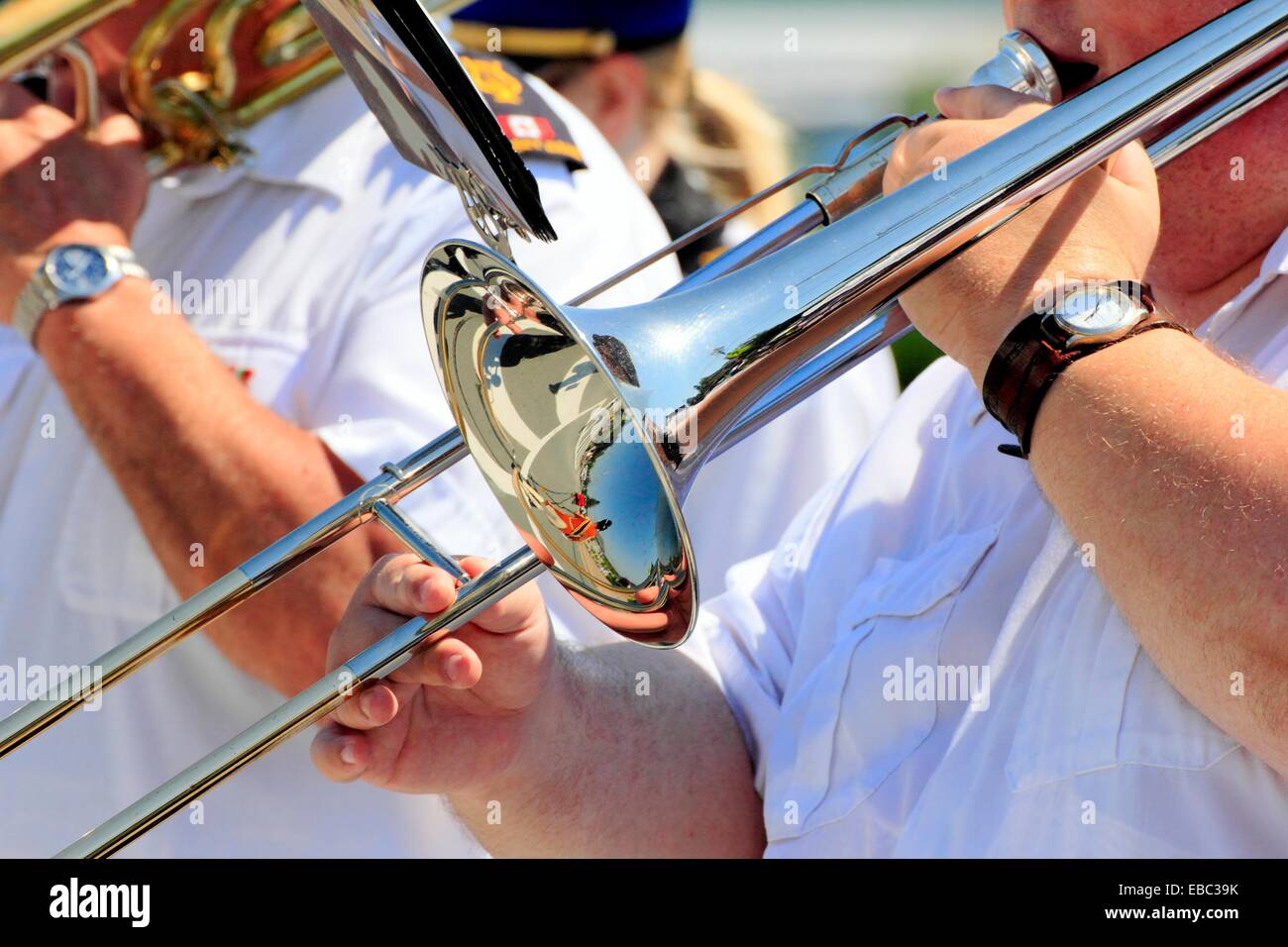 A male musician playing the trombone in a marching band in a parade