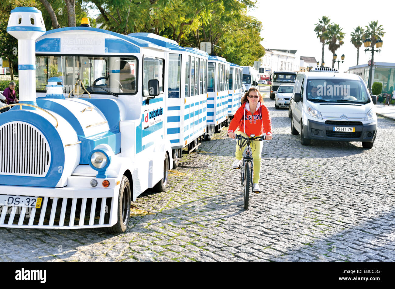 Portugal, Algarve: Touristic train of Delgaturis, biker and cars passing  the Jardim Manuel Bivar in Faro Stock Photo