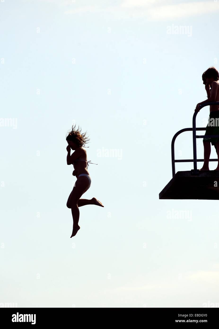 Single woman jumping from diving platform to waters of Geneva Lake