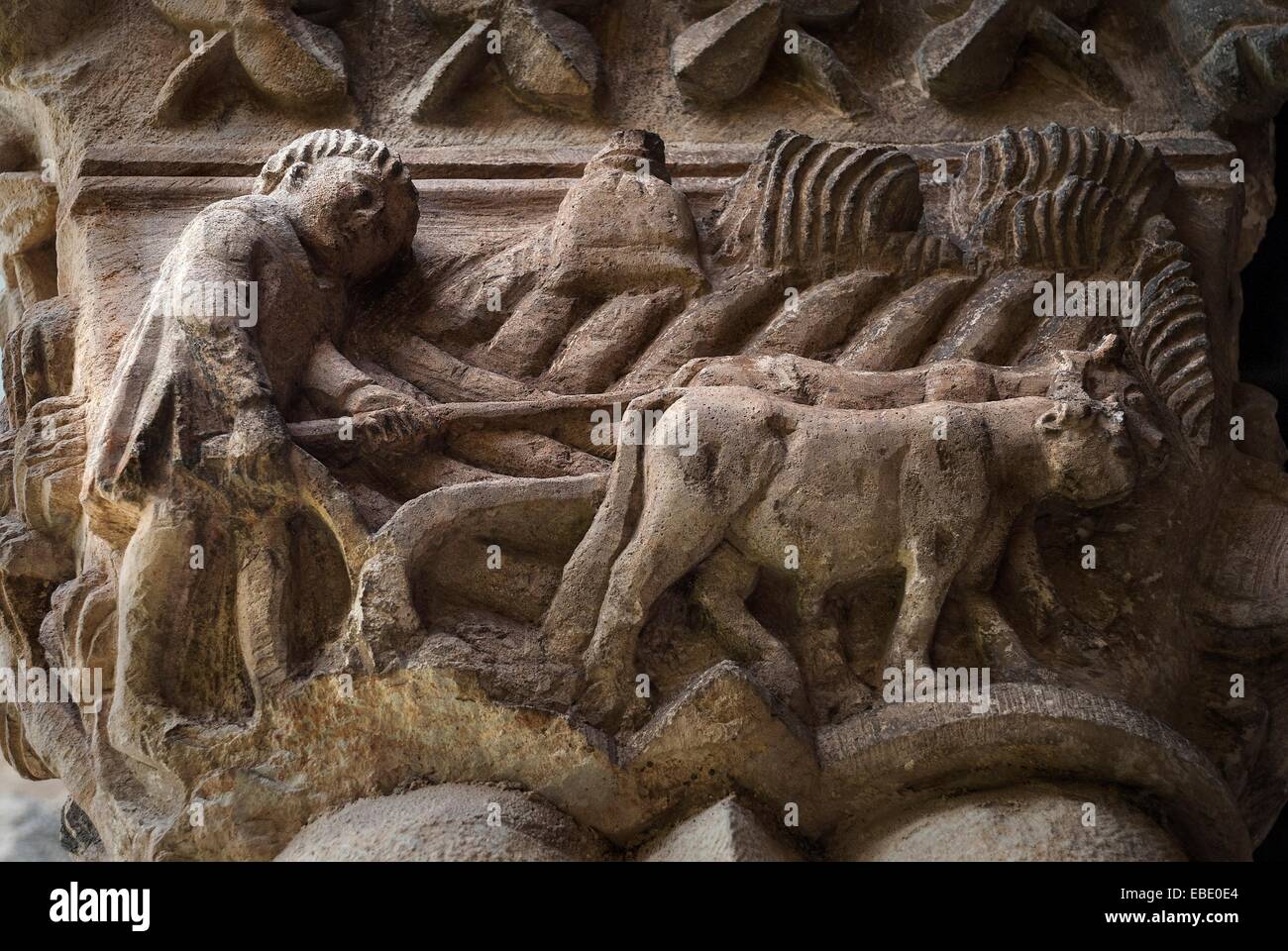 Farmer plowing with a pair of oxen. Iconographic motif carved into a capital in the church of Santa MarÃa de Nieva. Stock Photo