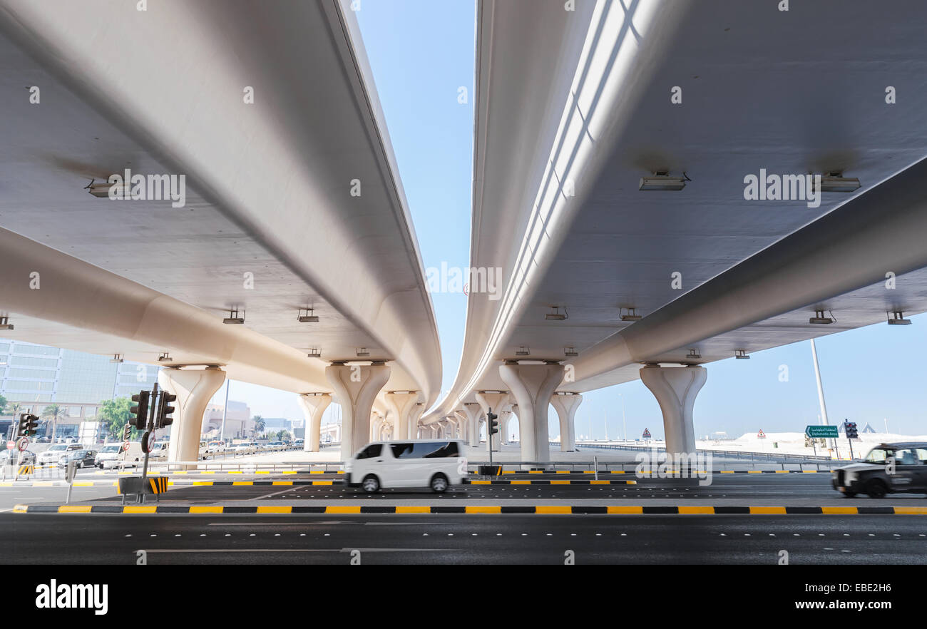 Cars drive on the highway under automotive bridges. City transportation of Manama, Bahrain Stock Photo