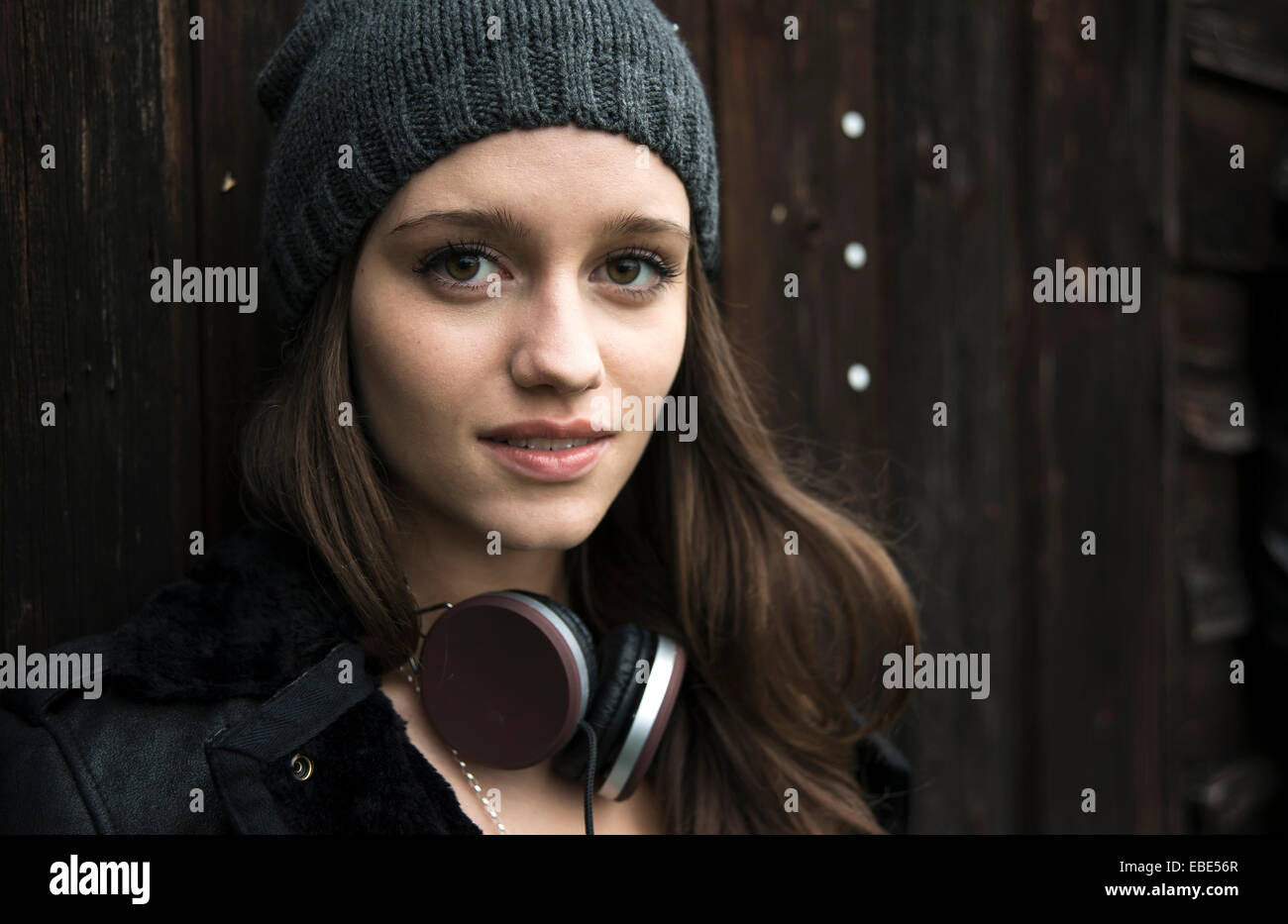 Close-up portrait of teenage girl outdoors, wearing hat and headphones around neck, looking at camera and smiling, Germany Stock Photo