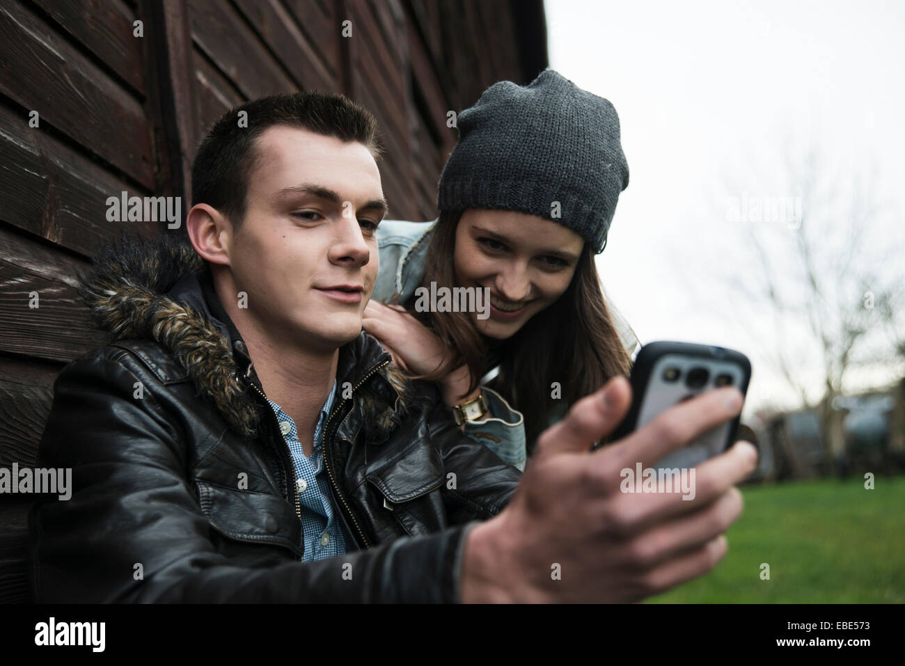 Close-up of young man and teenage girl outdoors, looking at cell phone, Germany Stock Photo