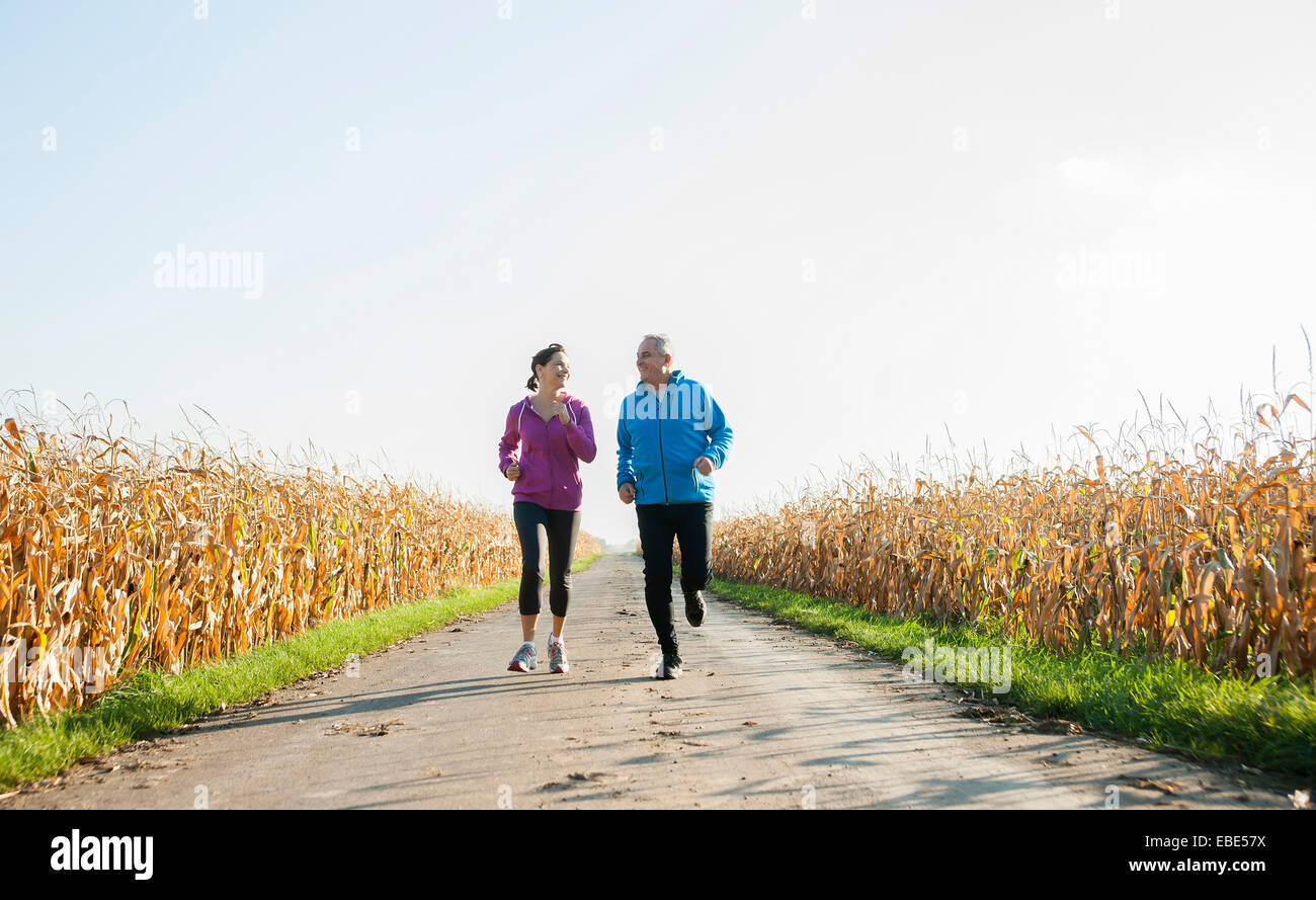 Adult couple running on country road, Germany Stock Photo