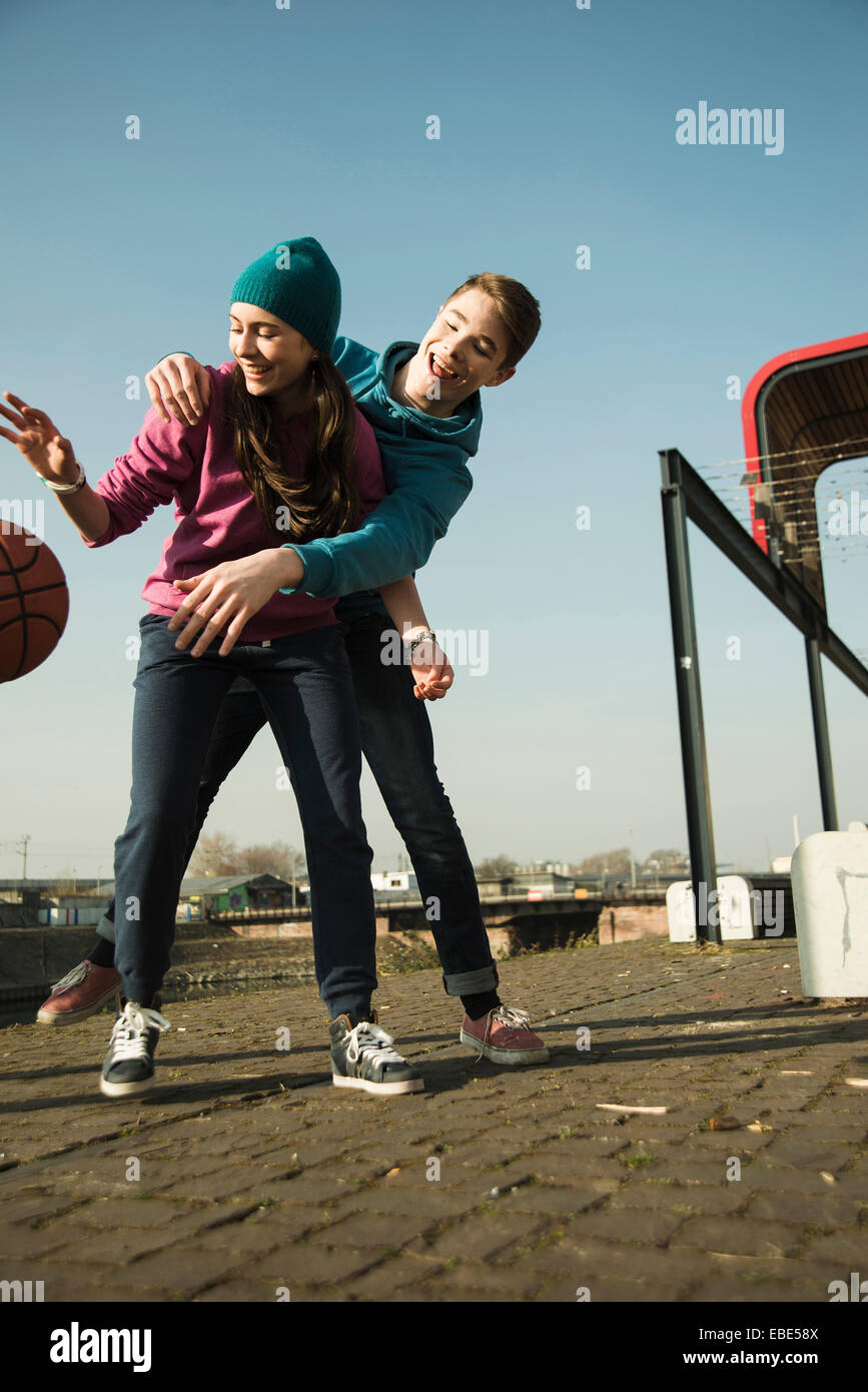 Teenage boy and girl playing basketball outdoors, industrial area, Mannheilm, Germany Stock Photo