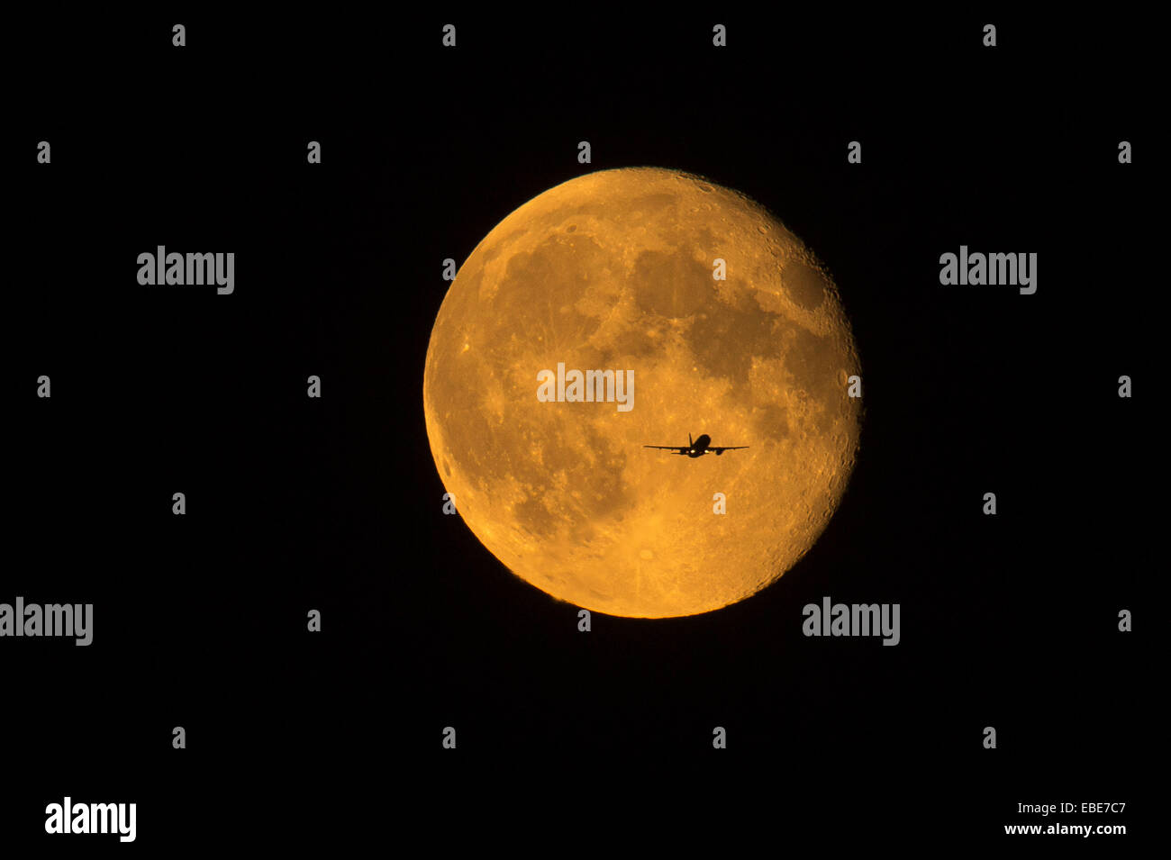 Pic shows an aeroplane flying across the patch of the september harvest moon 2014. Image shot from Watford in Hertfordshire Stock Photo