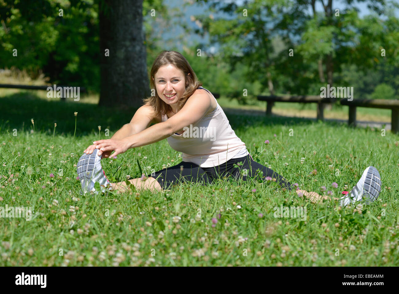 sporty young woman makes stretching exercises on grass Stock Photo - Alamy