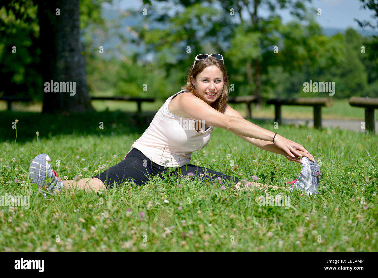 sporty young woman makes stretching exercises on grass Stock Photo - Alamy