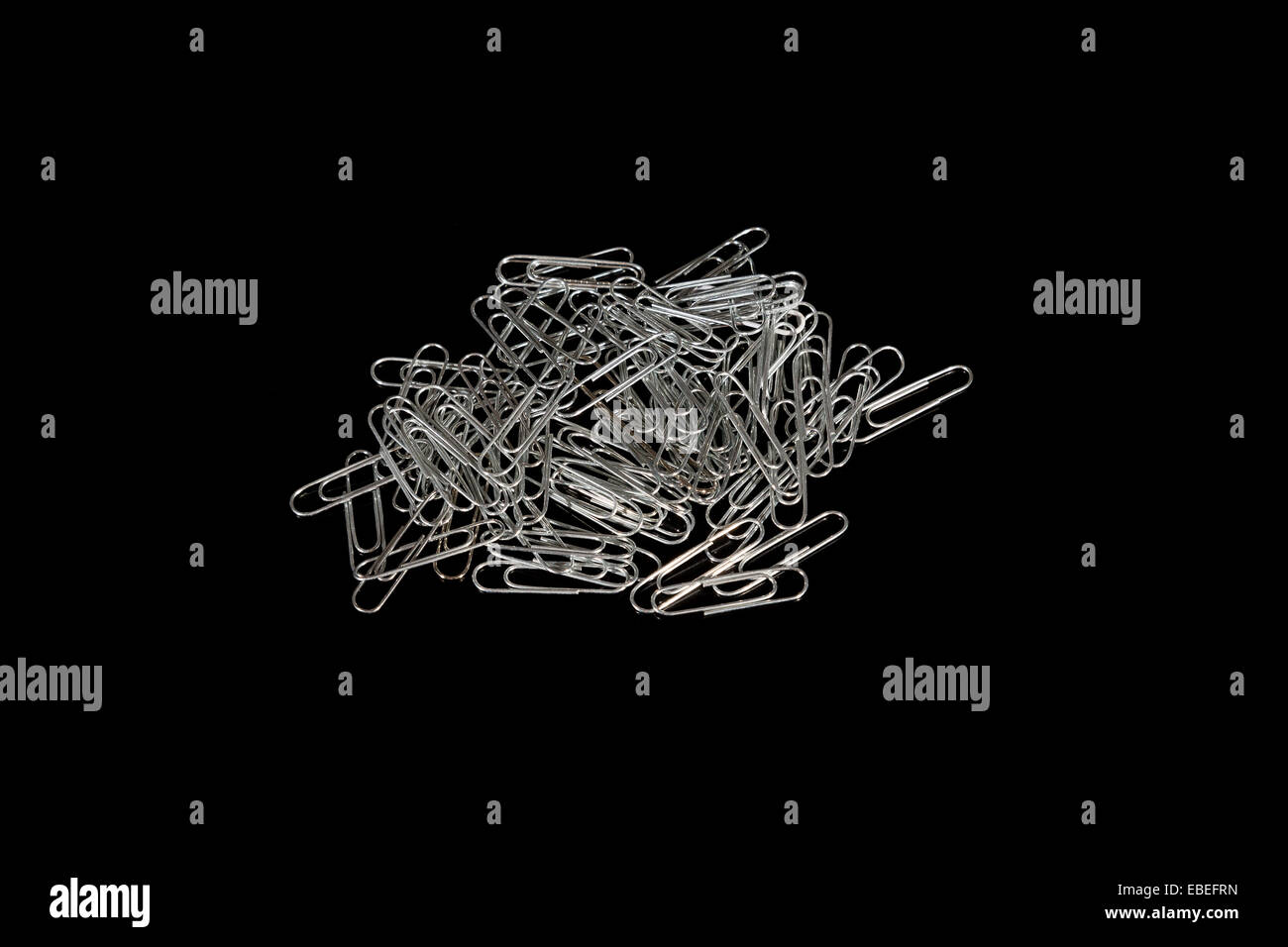 Closeup to a pile of silver paperclips on a black background Stock Photo