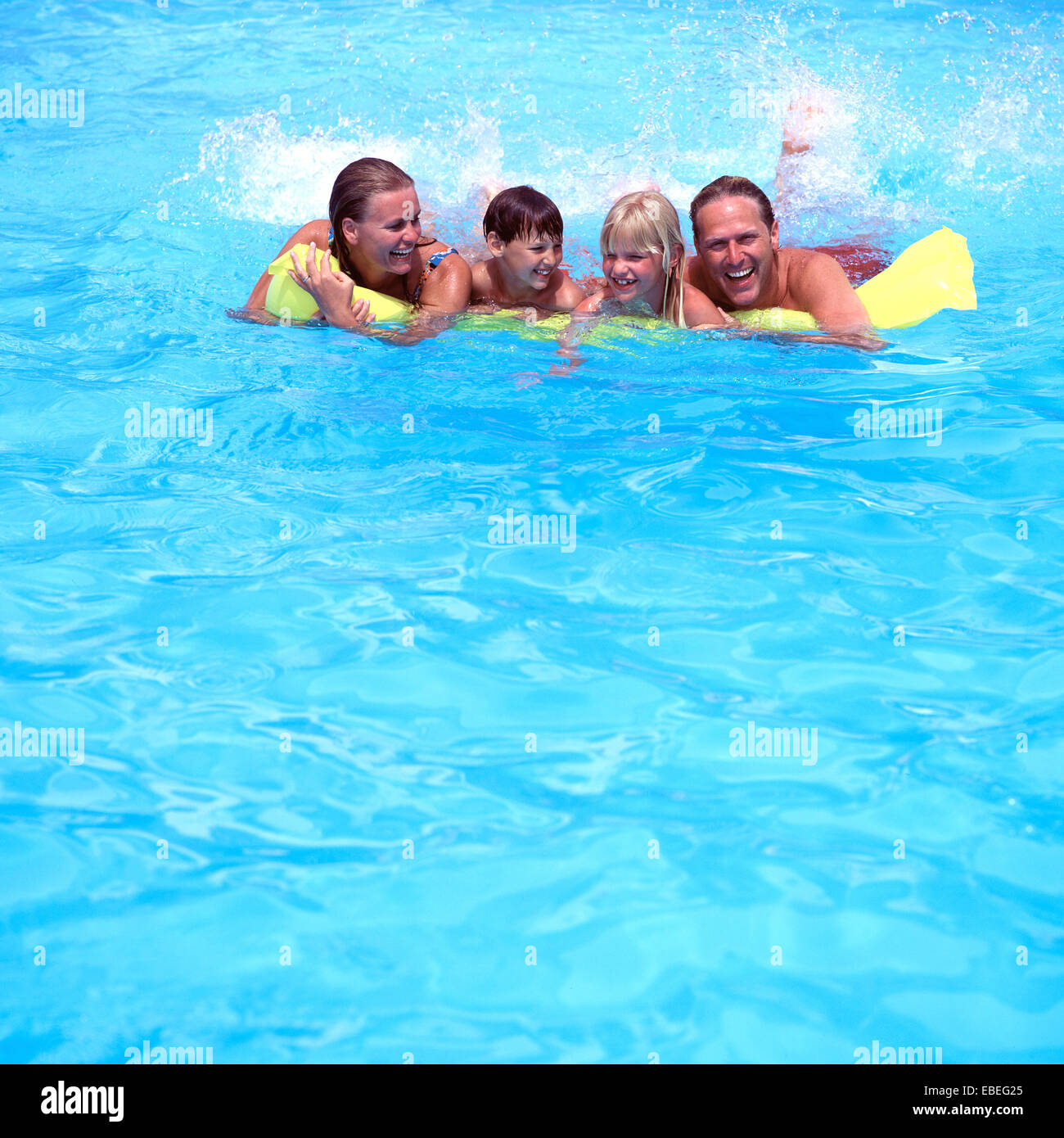 FAMILY ON LILO IN POOL Stock Photo