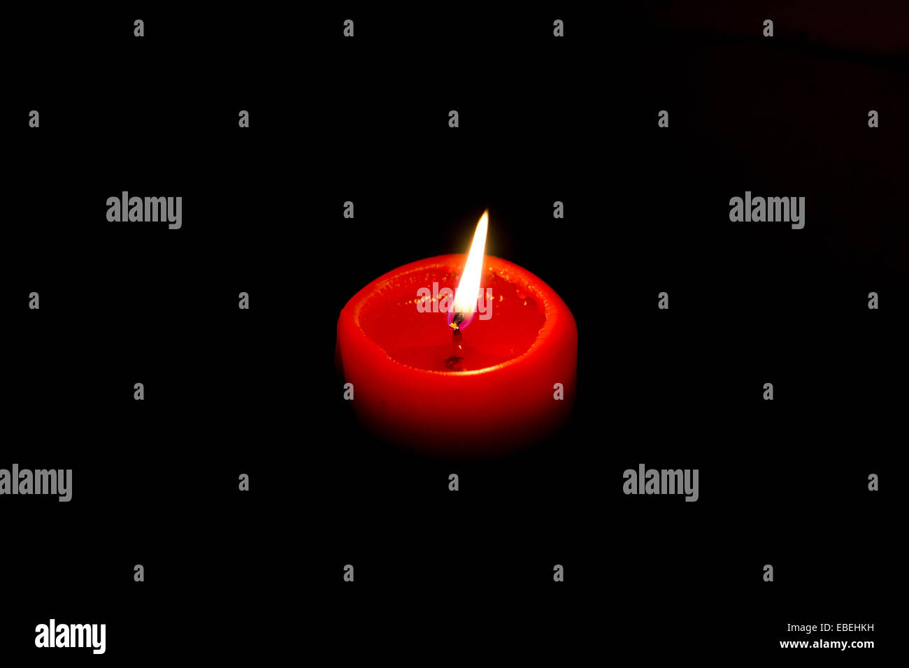 Burning red candle with a flame Stock Photo