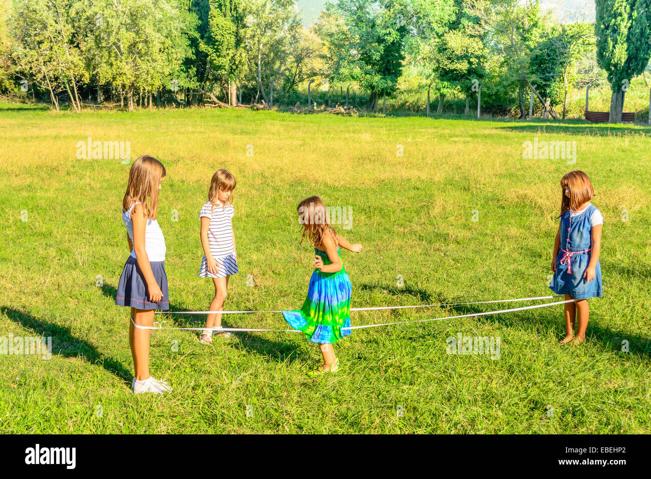 Four little girls playing elastics in the park Stock Photo Alamy