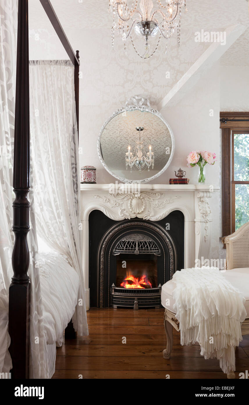 Elegant white bedroom with gas fireplace and canopy bed, Long Beach Island, New Jersey, USA Stock Photo