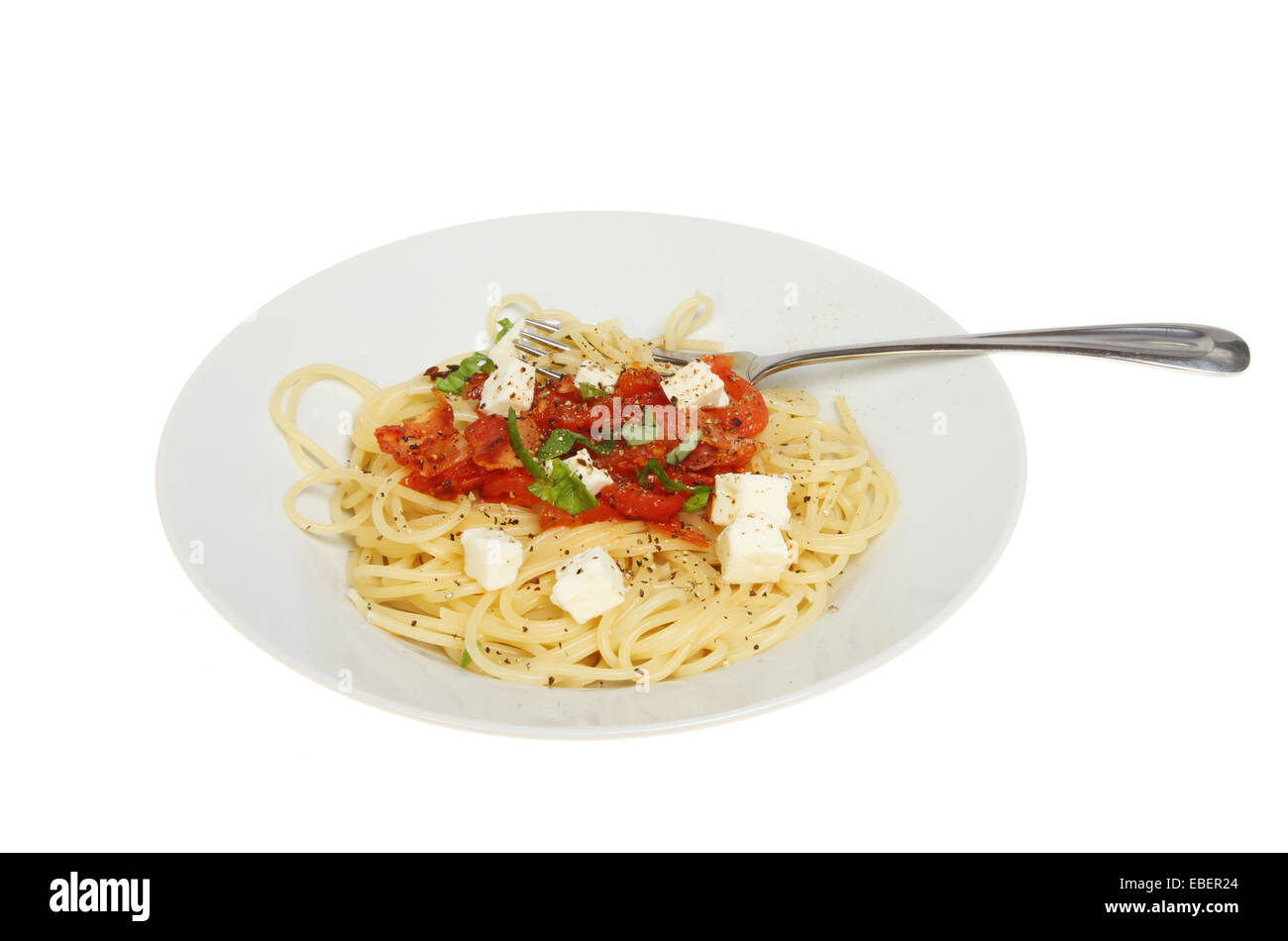 Panchetta,tomato,basil and feta cheese with spaghetti on a plate with a fork isolated against white Stock Photo
