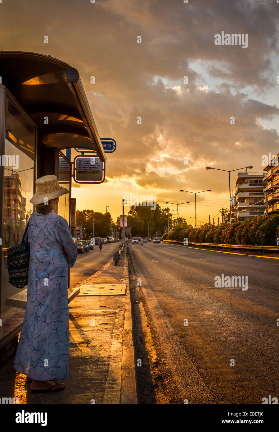 A lady waiting for the bus in sunset. Stock Photo